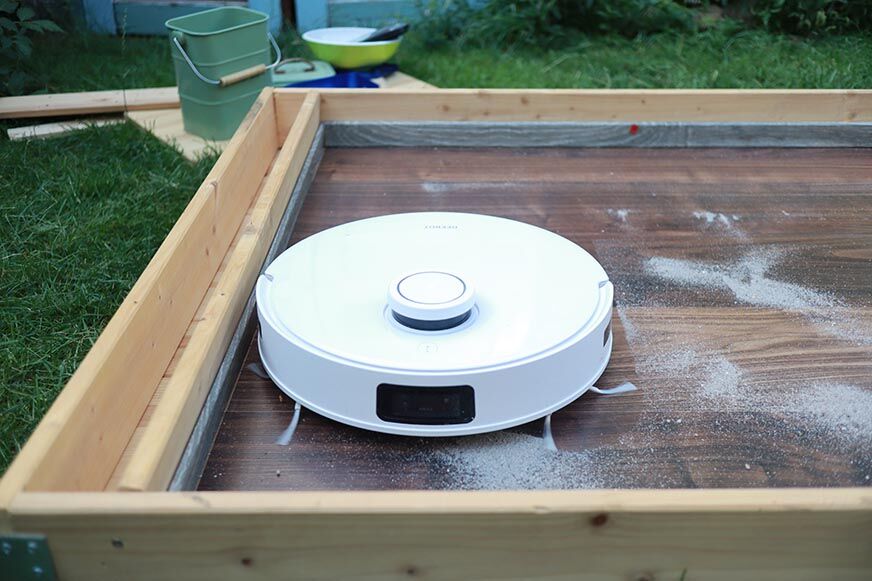 Ecovacs Deebot T10 reinigt Sand auf einem Laminatboden im Saugtest.